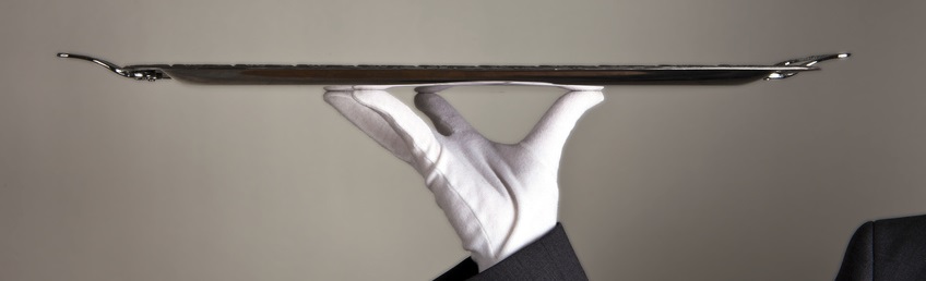 Ein Ober mit weißem Handschuh trägt ein silbernes Tablett: Symbolbild für "Service"
