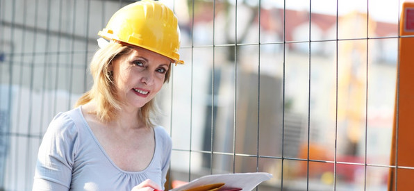 Eine Frau mit Schutzhelm auf einer Baustelle - Symbolbild 