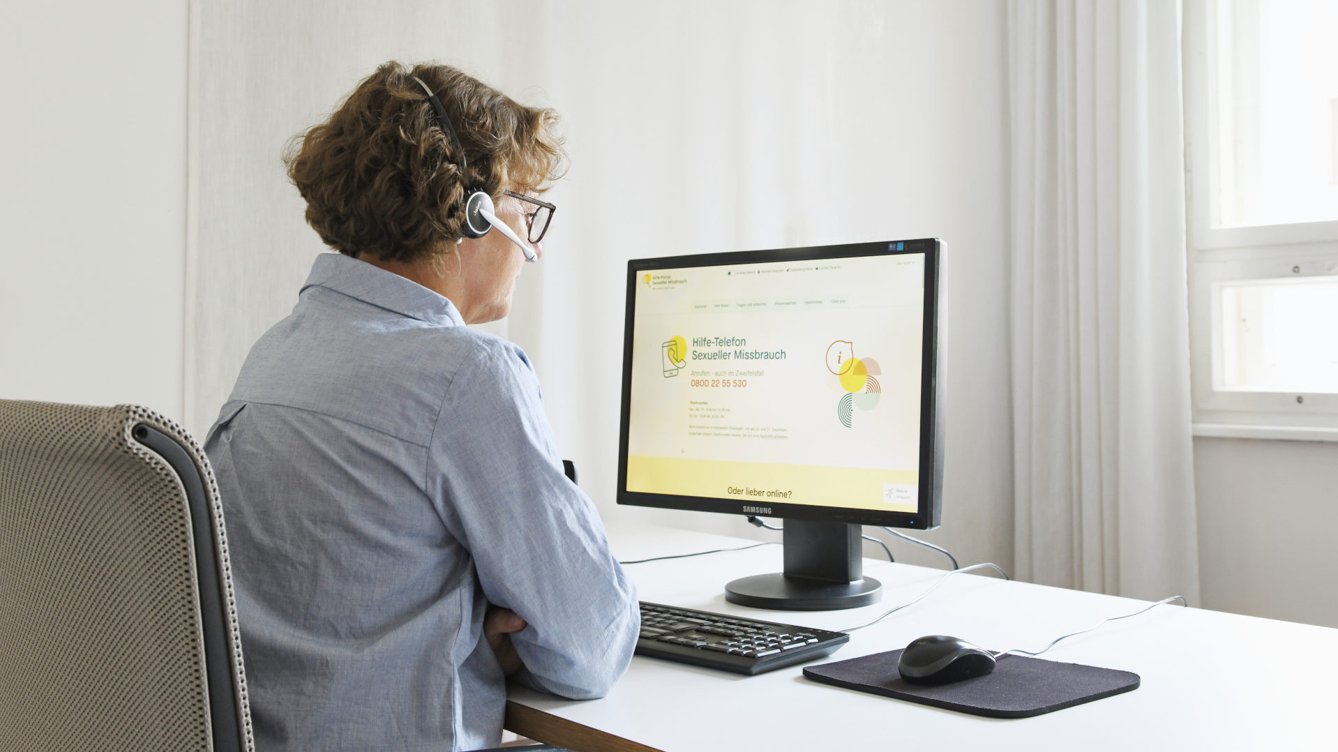 Symbolbild: Frau arbeitet mit Headset vor einem Monitor