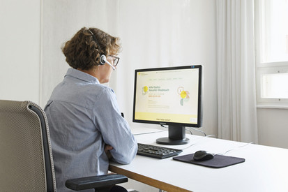 Symbolbild: Frau arbeitet mit Headset vor einem Monitor