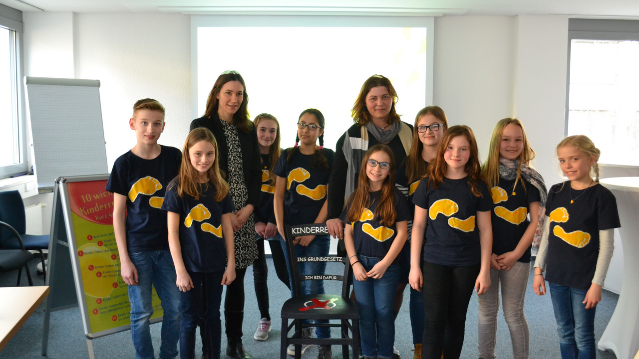 Ministerin Anne Spiegel bekommt von der Schülerinnen und Schülern der Grundschule Gau-Algesheim den Kinderrechte-Stuhl überreicht