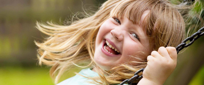 Ein lachendes Mädchen auf einer Schaukel - Symbolbild für "Gute Zukunft für alle Kinder und Eltern"