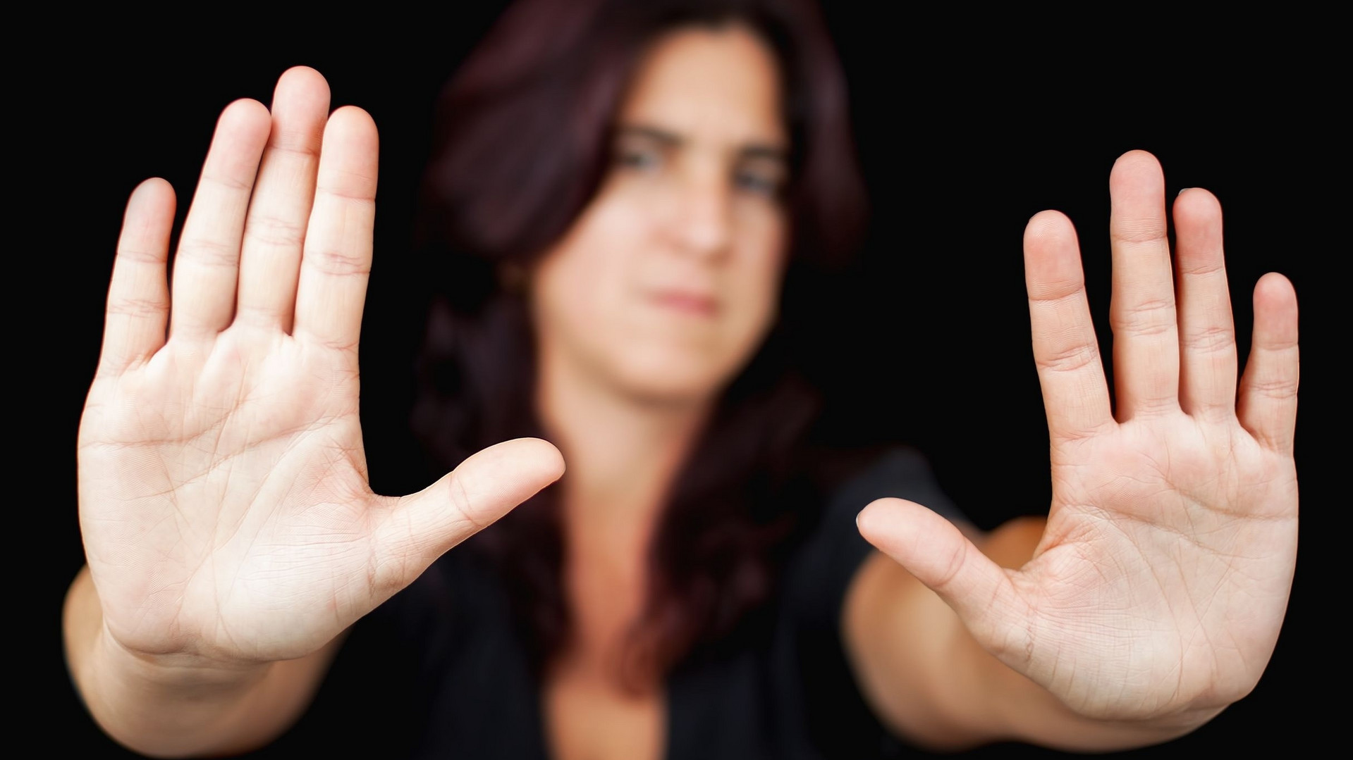 Symbolbild RIGG: eine Frau mit ausgesteckten Armen und erhobenen Händen: "Halt, stopp!"
