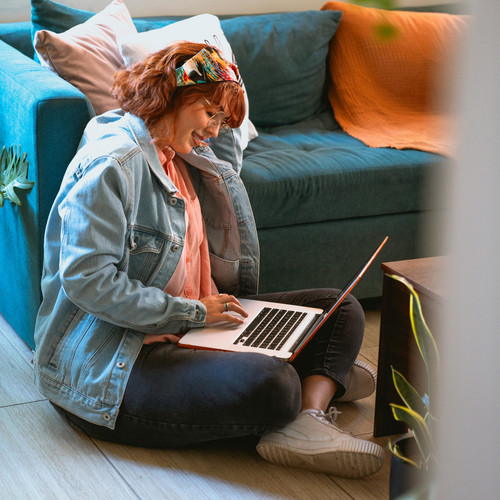 Symbolbild: Eine Frau sitzt auf dem Boden und arbeitet an Ihrem Laptop